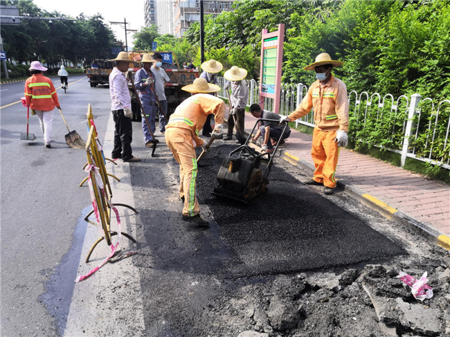 市政工作人员用沥青填补水毁路面（东堤路风采广场公交站处）.jpg