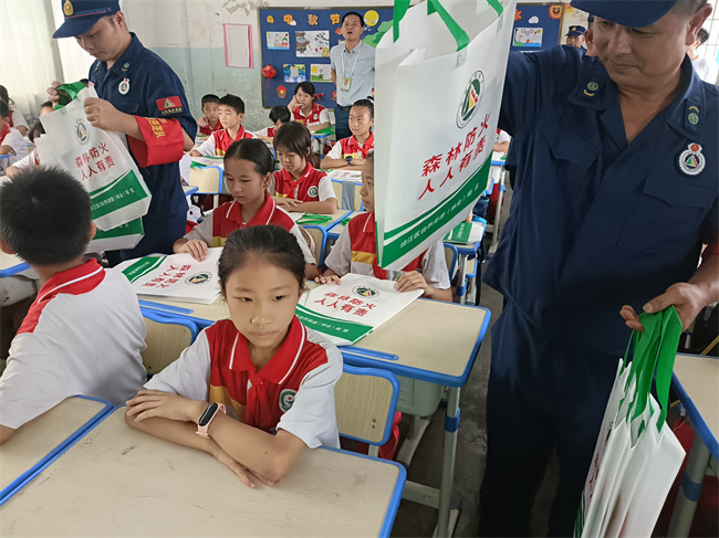 在犁市镇中心小学，工作人员向小学生们发放森林防火宣传资料.jpg