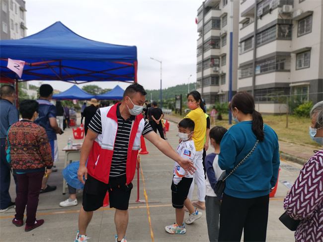 谭才军在花坪居核酸采样点引导群众保持间隔距离排队.jpg